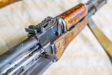 Kalıplı bir yüzeyde eski bir tüfek, ahşap zemin ve kabza, aşınma izleri olan metal bileşenler, kayıp ya da belirsiz uç, metin ya da başka bir nesne yok, silahın altında yumuşak gölgeler, yayılmış ışık kaynağı,