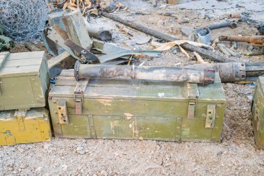 Askeri teçhizat, havan topu namlusu, mühimmat kutuları, kayalık yüzey, bitki döküntüleri, öğleden sonra geç saatlerde doğal aydınlatma, terk edilmiş, basit bir tarz. a