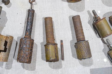 Eski metalik nesnelerin yakın plan görüntüsü, muhtemelen endüstriyel parçalar, bazılarında pas veya aşınma var, dokulu bir yüzey üzerinde uzanıyor.