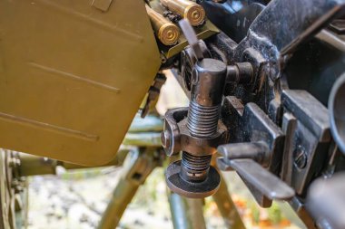 Yaylı ve levyeli koyu renk paleti de dahil olmak üzere birden fazla bileşeni olan karmaşık, endüstriyel mekanik bir montajın yakın plan görüntüsü. Işıklandırma bastırılmış. Çevrede ya da insanlar mevcut değil.