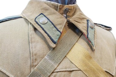 Promosyon amaçlı gösterilen antika askeri ceket muhtemelen koyu aksanlı açık kahverengi taban rengi, geniş yakalı ve göğüs kayışı dayanıklı kumaş görünür.