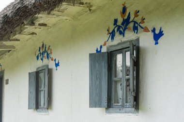 Kırsal, eski Avrupa köyü Beyaz ev sazdan çatılı, dekoratif mavi sanat eserleri, parmaklıklı açık ve kapalı pencereler, açık kapaklı levha, kırsal görünüm, iyi-anaerkil