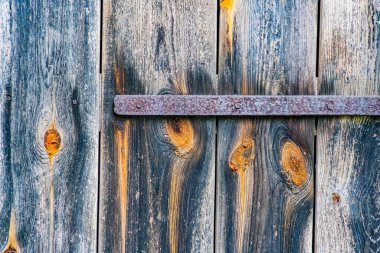 Orta Avrupa 'da bir köyde eski, yıpranmış ahşap bir ahır kapısına yakın plan. Çürüme ve katmanlardan dolayı çok boyutlu bir görünüm var. Görüntü bastırılmış, yaşlanmışlık kalitesini arttırıyor.