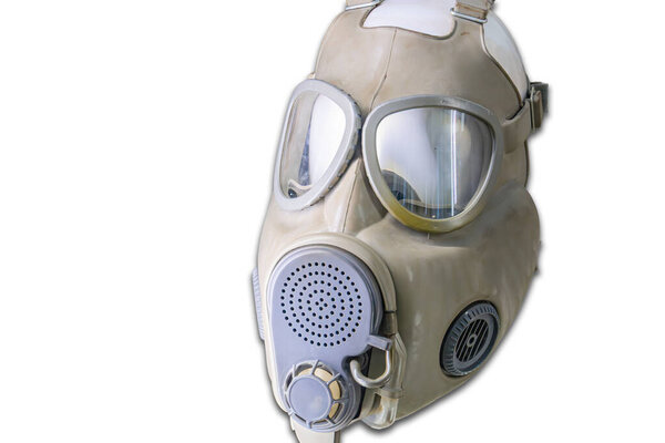 Бежевая антикварная военная противогаз маска с темно-тонированными линзами и несколькими фильтрами, в нейтральном освещении внутри помещений на светлом фоне
