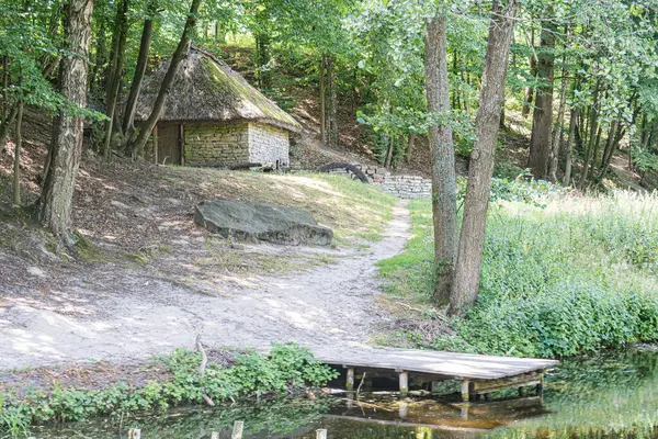 Huzurlu, eski Orta Avrupa köyü sazdan çatılı, taş yolu, dingin su yolu, ahşap rıhtım, yeşillik, kahverengiler ve ince maviler, hafif ışıklandırma, insan yok