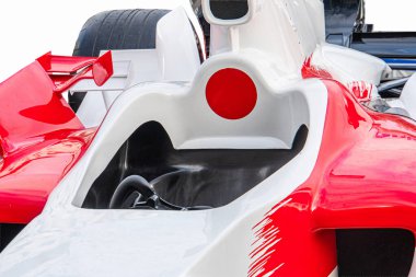 Pürüzsüz beyaz bir Formula 1 yarış arabasının açılı çekimi. Kırmızı ve siyah aksanlı. Görünür kokpit ve yan hava alımı var.