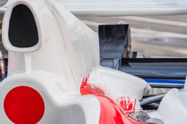 Formula 1 'in arka bölümünün yakın plan çekimi, kırmızı ve siyah aksanlı beyaz kaporta, aerodinamik elementler, kapalı bir ortamda karmaşık iç mekan bileşenleri