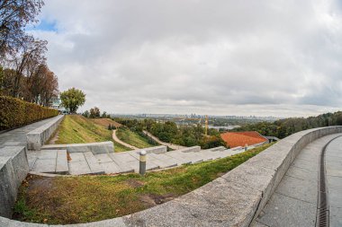 Öğleden sonra Kiev 'deki çimento yolu, manikürlü çimenler, alçak taş duvarlar ve sonbahar ağaçları ile bakımlı bir park ya da bahçe manzarası gerçekçi ve doğaldır.