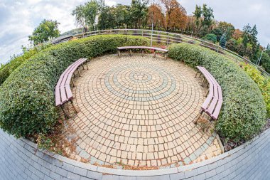 Kiev 'deki dairesel oturma alanının havadan görünüşü, merkezi beyaz sarmal desenli kırmızı tuğlalardan inşa edilmiş yeşil yapraklı ve kırmızı ahşap bir bank hafifçe kaldırılmış.