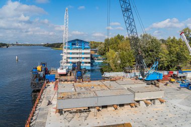 Kiev nehir kıyısı boyunca inşaat alanı Büyük mavi vinç, beton yapılar, çelik kirişler, ahşap destekler, döküntüler, tamamlanmamış binalar,