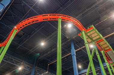 Hız treni, kırmızı raylı yeşil pist, dinamik döngüler ve kıvrımlar, sağlam yeşil sütunlar, yumuşak gölgeler, geniş görüş, birden fazla seviye, canlı renk, eğlence parkı ayarı