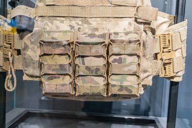 Zeytin yeşili, çöl kamuflaj yeleği manken standında sergileniyor fermuarlı ve kayışlı kumaş inşaatı ekipman için cepleri ve cepleri var.