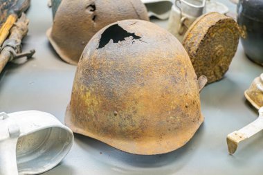 Paslı miğfer koleksiyonu, değişik şekil ve boyutlarda, koyu gri bir yüzeye saçılmış, aşınma ve aşınma belirtileri gösteriyor.