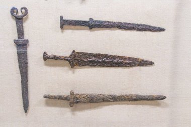 Bir ışık, kumaş desenli bir yüzey üzerinde sergilenen antik kılıç koleksiyonu paslı bıçaklarla yaşlılık belirtileri gösterir hatta aydınlatma bile yumuşak gölgeler ve yüksek gölgeler bırakır.