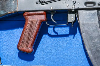 Mavi ekran yüzey şarjöründe ahşap kabzalı koyu metal bir tüfeğin yakın plan görüntüsü iyi, ön yırtık ve demiryolu sistemi markalaşma ya da görünür başka nesne yok Doğal ışıklandırma kalıpları