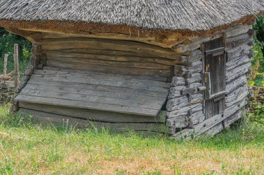 Sazlı çatılı antik ahşap bina, yemyeşil bitki örtüsü, bulutlu gökyüzü, dağınık aydınlatma, çimenli zemin ve Orta Avrupa 'da görülebilir bir köyde hiç kimse yok.