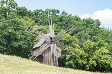 Bereketli, bakımlı yeşil bir tarlada bulunan ahşap Hollanda yel değirmeninin yapısında karmaşık detaylı, sağlam ahşap kirişlerle sekiz yelken bulunur ve küçük bir kubbeyle sonuçlanır.