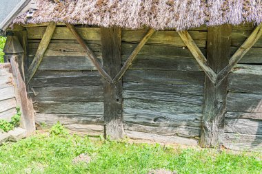 Eski bir Avrupa köyünde eski ahşap sazdan bir bina, yeşil çimenler doğal gün ışığı altında çevrili