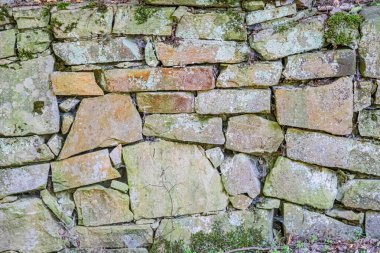 Orta Avrupa 'da eski bir taş duvarın yakın çekimi, çeşitli boyutlarda, şekillerde ve gri ile kahverengi taşların renklerini, görülebilir tahıl dokusunu, yıpranma belirtilerini ve görülebilir bir nesne ya da peo yok.