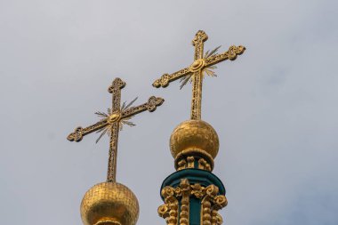 Eski Avrupa kilise kulesinde altın haç, bulutlu gökyüzü altında, zengin mimari detay, süslü üs