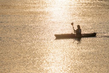 Günbatımında kayak yapan kişi, basit kano tasarımı, kürek çekme, ılık ışıklandırma, ışıldayan su, canlı renkler mavi, kırmızı, sarı, portakal, derinlik perspektifi, sakin wa Kyiv, Ukrayna 06-05-2025