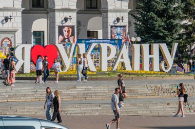 Kyiv, Ukrayna şehri Maidan Nezalezhnosti, Şafak veya alacakaranlık Büyük UKRAINE tabelasına bayılıyorum Mavi arka planda koyu kırmızı yazıyla Ağaçlar üzerinde yürüyen insanlar Kyiv, Ukrayna 07-05-2025