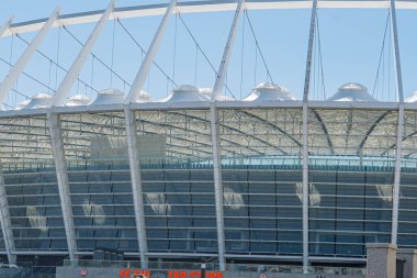 Ukrayna 'nın başkenti Kyiv' deki modern, gri ve beyaz Olimpiyat Stadyumu soyut desenli beyaz kirişlerle desteklenmektedir. Açık mavi gökyüzü Kyiv, Ukrayna 07-06-2025