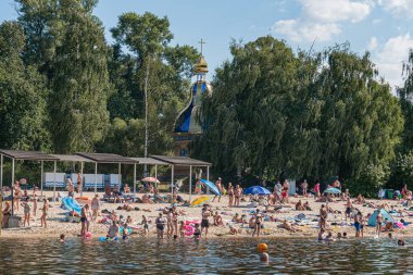 Kyiv, Ukrayna 'da kumlu bir sahilde güneşli, güneşli bir gün. Sayısız renkli şemsiyeler kıyıya vuruyor, gölge sağlıyor ve canlı bir atmosfere katkıda bulunuyor. İnsanlar Kyiv, Ukrayna 07-12-2025