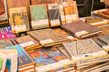 Özet A tablosu Ukrayna, Kyiv, 06-01-2025 'te yumuşak ışıklandırma altında çeşitli renkli, desenli kapaklı kitapları sergiliyor.