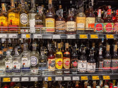 Ukrayna, Kyiv, Ukrayna 06-30-2025 'in sıcak ışıklandırmasıyla aydınlatılan çeşitli boyut ve şekillerde çeşitli şişelerin yer aldığı canlı alkol deposu vitrinleri.