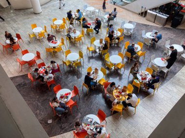 Kiev 'deki turuncu ve sarı tonlu süpermarket, masaların etrafına dağınık kırmızı ve sarı sandalyeler konuşmalar yapan insanlar, çeşitli Kyiv, Ukrayna 07-19-2025