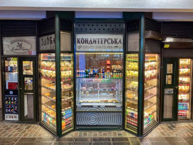 Bir kahve dükkanının vitrininde siyah çerçeveli vitrin, içecekler, paketlenmiş atıştırmalıklar ve dilimlenmiş ekmek ürünleri baskın siyah renk paleti, whi Kyiv, Ukrayna 07-19-2025