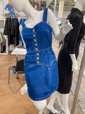 Moda sergisi, birden fazla manken giysi sergisi merkezi manken pliseli ve düğmeli kot elbise, parlak ışıklandırma, f Kyiv, Ukrayna 07-31-2025