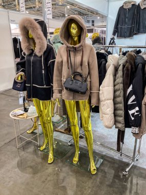 Bir galeride iki mankenin yer aldığı canlı bir giysi sergisi biri ayakta diğeri ise bir kaidede oturan sahte Fu Kyiv, Ukrayna 07-31-2025 model bej kapüşonlu bir kapüşon giyiyor.