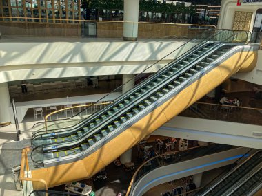 Modern kapalı alışveriş merkezi, TSUM Kiev, cam kaplı yürüyen merdivenlerle açık atrium tasarımı içeriyor. Çağdaş yürüyen merdivenlerde sarı güvenlik şeritleri, cilalanmış Kyiv, Ukrayna 08-03-2025