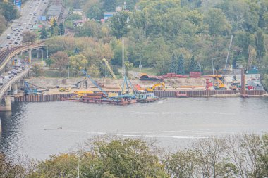 Suların kenarında inşaat alanı, muhtemelen bir kazıcı ya da vinç gibi ağır makineler için, sarı ve siyah renkler, yakınlarda yüzen çelik parçası, Industria Kyiv, Ukrayna 10-10-2024