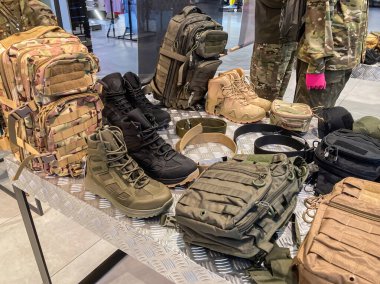 Açık bir sırt çantası, siyah botlar, kamuflaj giysileri, eldivenler ve mühimmatın yer aldığı metal bir ızgarada Ukrayna askeri teçhizatı sergileniyor