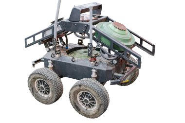 Robot mayınlı zemin dronu off-road tekerlekleri ve merkezi yuvarlak gövdesi ile düz metalik bir platforma sahip ve kontrollü aydınlatma koşulları altında çalışıyor.