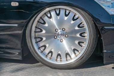 Parlak krom jant kapağı içeren iyi korunmuş bir araba arka tekerleğinin yakın plan resmi Derinlik perspektifi tekerleğin merkezini ve kenarlarını vurgular Görünür metin tarafından sağlanan ek bilgi yok