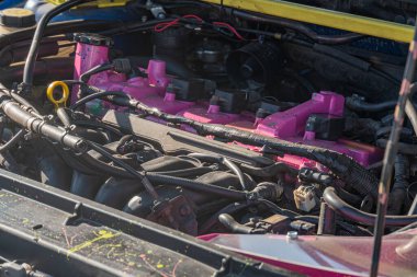 Araçtaki pembe motor kompartımanının yakın plan görüntüsü, kablolar ve kablolarla görünümü gösteriyor. Doğal, dağınık ışıklandırma, insan aktivitesi veya metni yok.