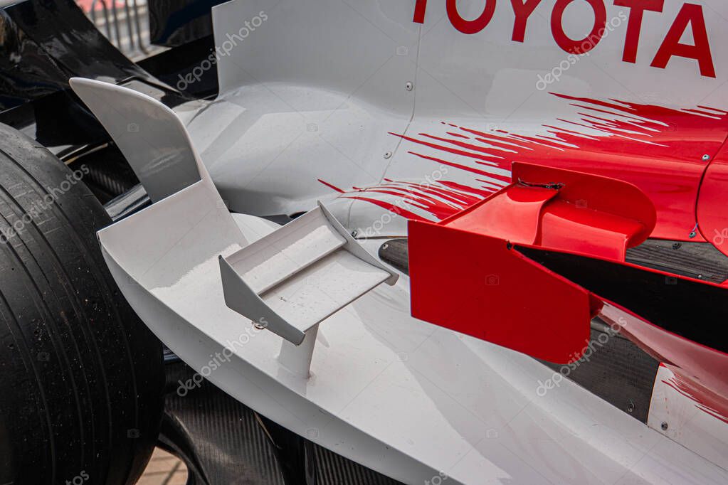 Close-up of a white and red Formula 1 Toyota TF-108 car, showcasing sleek aerodynamic design, natural lighting, outdoor setting pit lane or garage, no other object Kyiv, Ukraine 10-10-2024