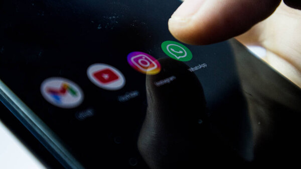 Sukabumi, Indonesia- November 28, 2023 : Finger pressing Whatsapp icon on black Background