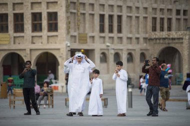 Doha, Katar - Mart 05, 2019: Geleneksel giyimli Katar ailesi eski pazar pazarı Souk Waqif 'te takılır..