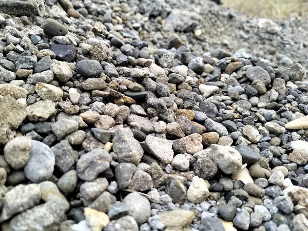 Gray gravel stones for the construction industry. Mound of granite gravel, stones, crushed stone close-up. Rough seamless texture, construction material background.