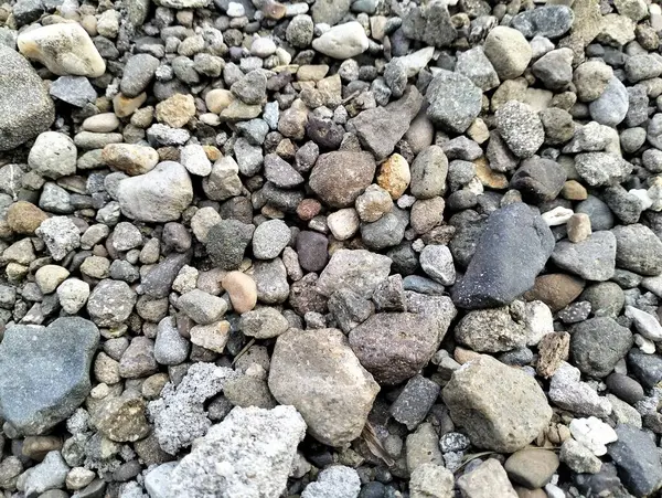 Gray gravel stones for the construction industry. Mound of granite gravel, stones, crushed stone close-up. Rough seamless texture, construction material background.