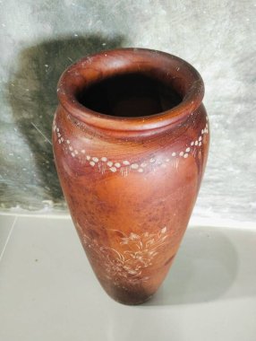 Kahverengi çiçek motifli ahşap bir vazo. Kahverengi ahşap bir vazoya karşı aci çimento duvar arkası