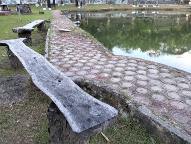 Parktaki ahşap bank ya da havuzun yanındaki bahçe, oturma, dinlenme ve dinlenme için kullanışlı olabilecek yaratıcı iç koltuk tasarımı, güzel doğa arka planı..