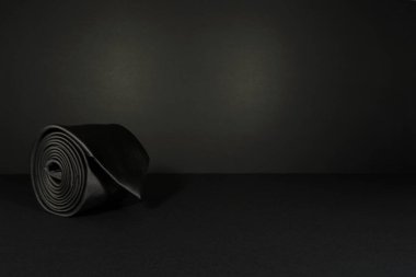 Düz kumaş siyah kravat siyah arkaplan yakın plan görünüm kopyalama alanı üzerinde rulo 