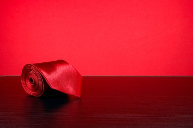 Kırmızı arkaplan karşısında kırmızı bir kravat yuvarlandı 