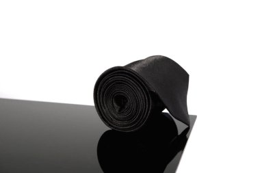 Yansıma yüzeyi üzerinde siyah bir kravat yuvarlandı. Yakından tek bir nesne görüntüsü 